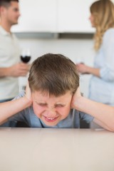 Fototapeta premium Furstrated boy covering ears while parents arguing