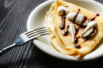 Closeup of chocolate pancakes with whipped cream