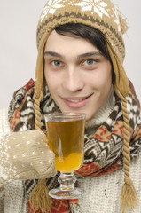 Man wearing sweater, gloves, scarf, hat, drinking cup of tea