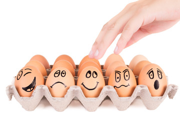Funny faces painted on brown eggs in a tray