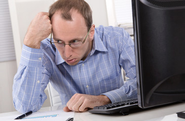 Mann frustriert und deprimiert in seinem Büro vor dem Computer