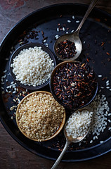 Various types of rice on old spoons and in cups