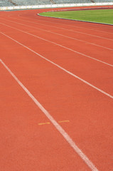 Orange racecourse with white line and green yard.