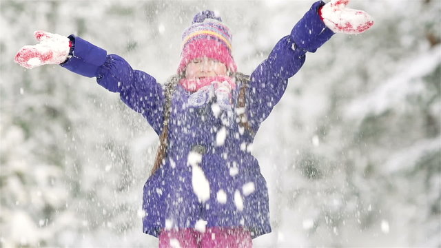 Medium slowmo shot of Caucasian girl tossing snow in winter park. Perfect for lifestyle, winter activities, family moments, seasonal content, carefree play