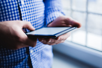 The man uses a tablet PC. Modern gadget in hand.