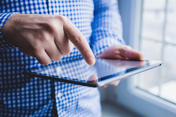 The man uses a tablet PC. Modern gadget in hand.