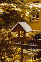 Wooden bird feeder in winter garden. Evening scenery