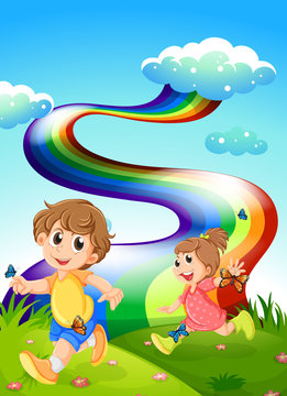 Kids walking at the hill with a rainbow in the sky