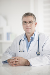 Portrait of handsome mature doctor in office