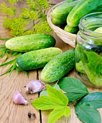 Cucumbers in jar and a wicker basket with leaves