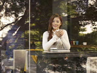 woman in cafe, holding coffee cup and smiling