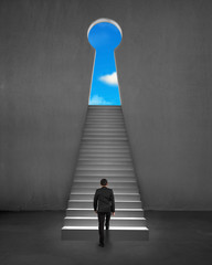 Businessman climbing on stair to key shape door with blue sky