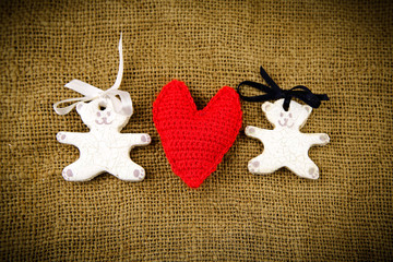Two white bears with red handmade heart on the sacking backgroun