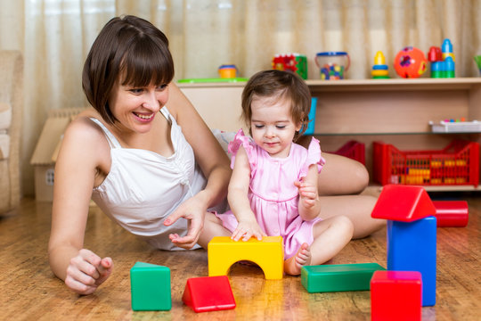mother and kid play with building block toys at home