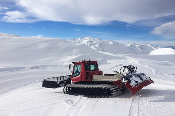 Modern red snow groomer in a sunny day