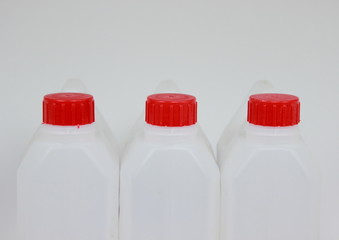 Three empty jerrycans of white plastic with red lids