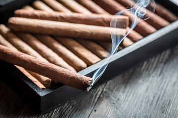 Burning cigar on wooden humidor