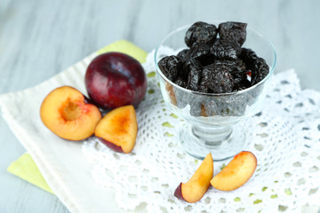 Fresh and dried plums in glass bowl