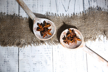 Star anise in wooden spoon, on wooden background