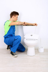 Plumber with toilet plunger on light background