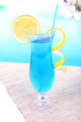 Glass of cocktail on table on light blue background