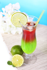 Glass of cocktail on table on light blue background