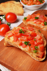 Delicious bruschetta with tomatoes on cutting board close-up