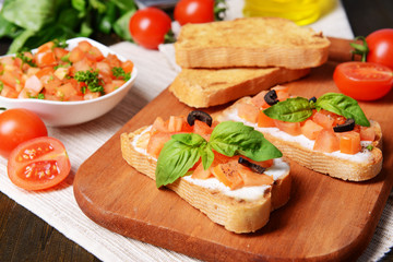 Delicious bruschetta with tomatoes on cutting board close-up