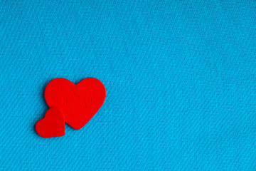 Red wooden decorative hearts on blue cloth background.