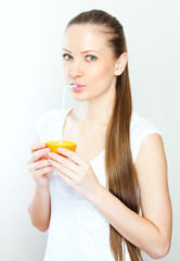 Attractive smiling young woman drinking orange juice straight fr
