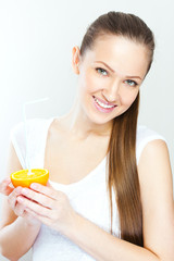 Attractive smiling young woman drinking orange juice straight fr