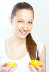 Attractive smiling young woman drinking orange juice straight fr