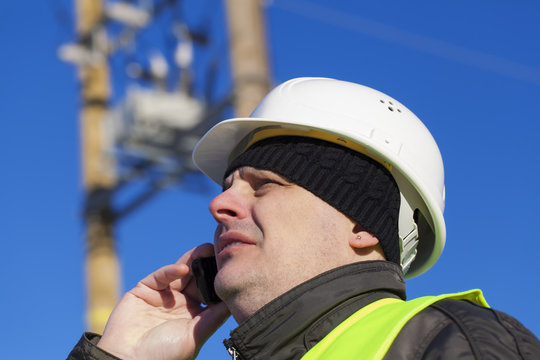 Electrical Engineer with cell phone near transformer