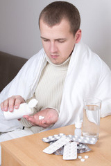 young attractive ill man taking pills in his living room