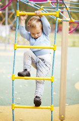 Cute little boy climbing on a jungle gym