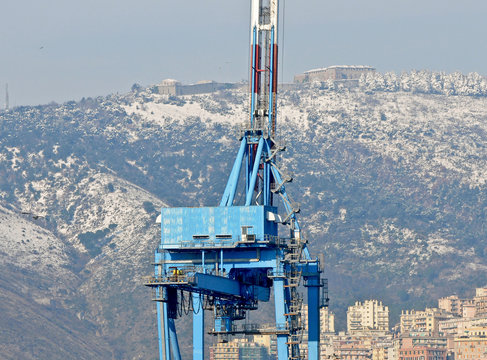 Una gru portuale con la neve sulle colline della citt&agrave;