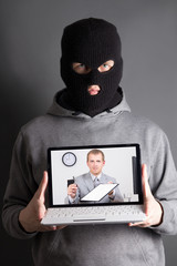 masked man with laptop - concept picture of internet crime