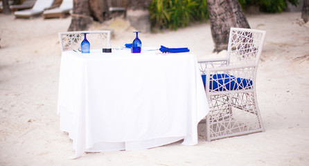 Summer empty open air table set for dinner on white beach
