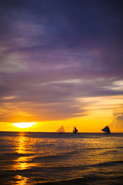 Colorful beautiful sunset with sailboat on the horizon in