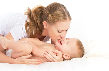 happy family mother and baby having fun playing, laughing on bed