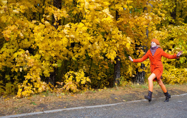 Fototapeta premium Girl in orange coat running in the yellow autumn forest.