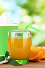 Glass of juice, citrus press and ripe orange