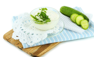 Cucumber yogurt in bowl, on wooden board, isolated on white