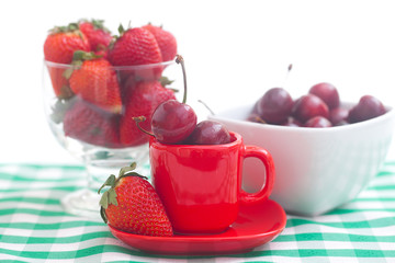 Cherries and strawberry in a ceramic and glass bowl on checkered