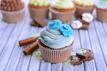 Tasty cupcakes with butter cream, on color wooden background
