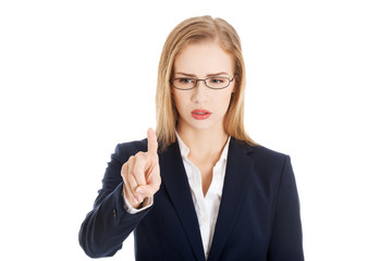 Confused business woman in eyeglasses is looking at her finger.