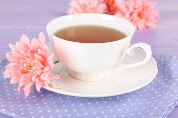 Pink chrysanthemums and cup of tea on wooden table