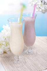 Milk shakes on table on light blue background