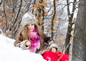 Happy little girl spending a nice time in winter forest