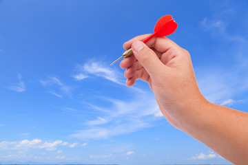 Hand with dart on blue sky